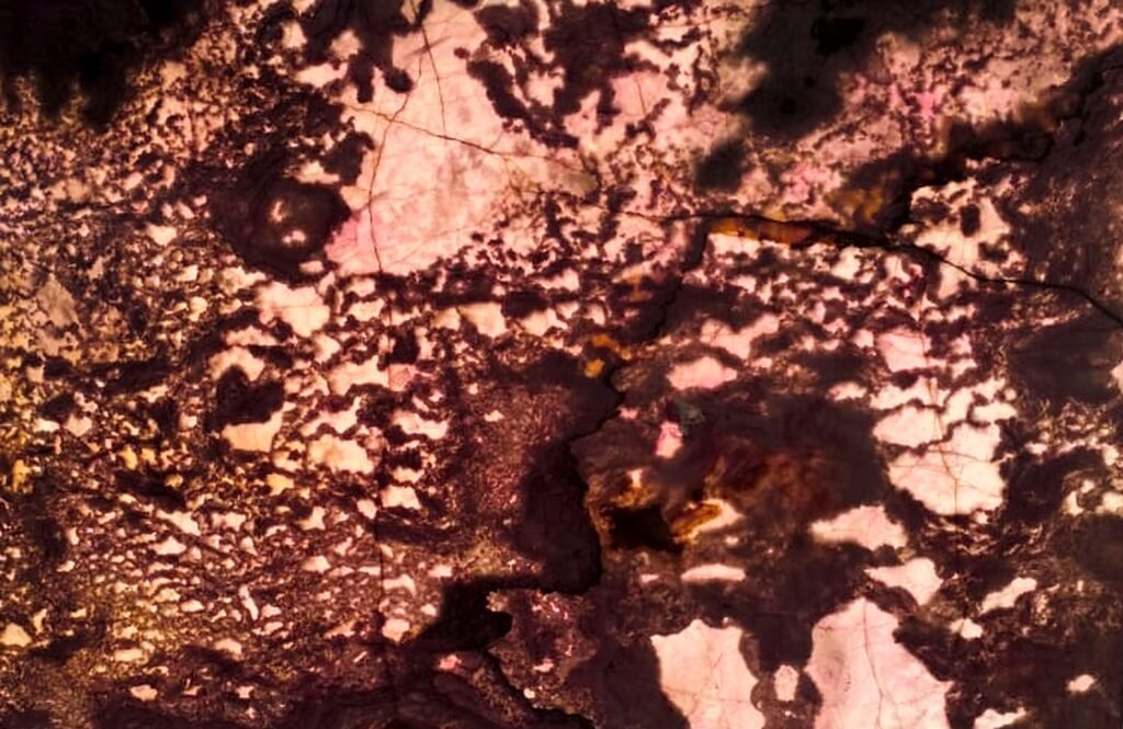 Backlit Exotic Pink Onyx slab glowing white, soft pink and warm amber through deep maroon veins