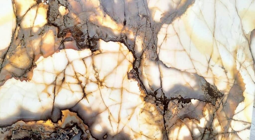 Backlit Deep Amber Onyx slab in deep amber, fiery gold, cocoa brown, warm cream and translucent ivory